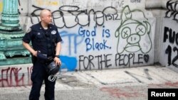 Un agente de la policía de Nueva York protege una de las zonas vandalizadas por los manifestantes que solicitan un recorte al presupuesto de la policía de la ciudad.