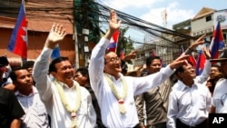 Cambodia's opposition leader Sam Rainsy, center, of the Cambodia National Rescue Party waves along with his party Vice President Kem Sokha, third from left, during a march in Phnom Penh, Cambodia, Sunday, March 30, 2014. 