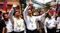 FILE PHOTO - Cambodia's opposition leader Sam Rainsy, center, of the Cambodia National Rescue Party waves along with his party Vice President Kem Sokha, third from left, during a march in Phnom Penh, Cambodia, Sunday, March 30, 2014. 