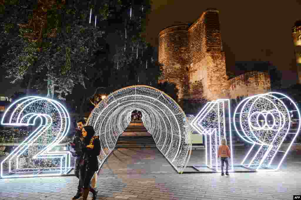 People walk past a &quot;2019&quot; new year decorations in front of the Maiden Tower in the Old city in central Baku, Azerbaijan, Dec. 22, 2018.