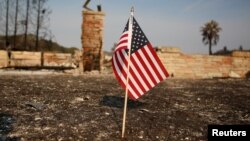 FILE - An American flag stands in front of a home destroyed after a wildfire tore through Santa Rosa, Calif., Oct. 15, 2017.