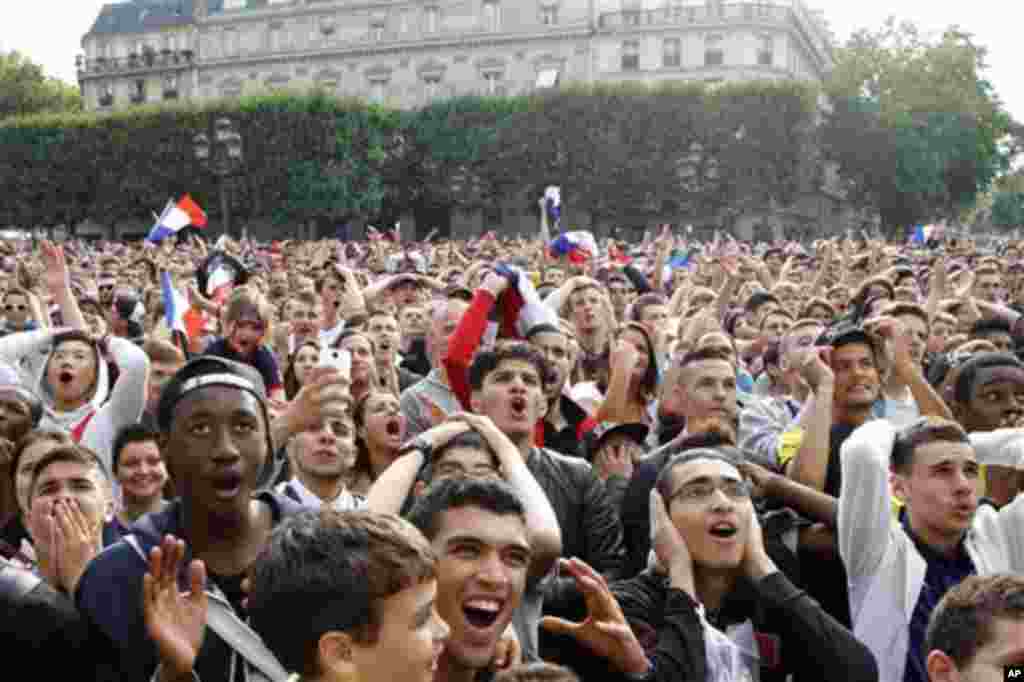 French soccer team supporters react as they watch the World Cup soccer match between France and Nigeria, being shown live on a giant screen, in front of Paris City Hall, Monday June 30, 2014. France went on to win the match 2-0. (AP Photo/Remy de la Mauvi