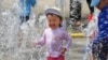 FILE - Children play in the water to cool off at a park in Yokohama, near Tokyo, Aug. 18, 2020. 