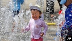 FILE - Children play in the water to cool off at a park in Yokohama, near Tokyo, Aug. 18, 2020. 