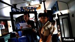 Members of an artistic group perform a "TV news show" on a public transportation bus in Caracas, Venezuela, June 10, 2017.