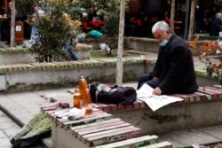 A street vendor reads a newspaper in Tirana, Albania, April 22, 2021. Albanians will elect 140 lawmakers Sunday in a vote considered key to convincing the EU to agree on starting full talks on Albanian membership.