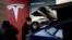 FILE PHOTO: Visitors wearing face masks check a China-made Tesla Model Y sport utility vehicle (SUV) at the electric vehicle maker's showroom in Beijing