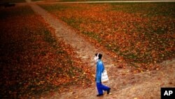 A woman, masked to prevent the spread of COVID-19, walks along Cinquantenaire park in Brussels, Oct. 23, 2020. Belgian Prime Minister Alexander De Croo stopped short Friday of imposing another full lockdown but introduced new restrictive measures.