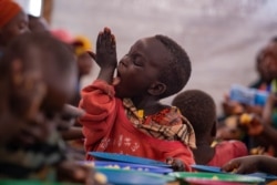 A young Burundian refugee licks his hand as he eats a meal at the Nyabitara Transit site in Ruyigi, Burundi, Oct. 3, 2019.