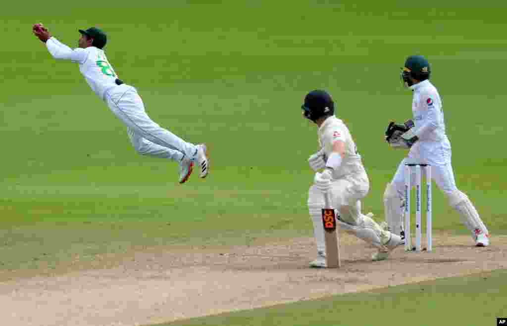 Pakistan&#39;s Asad Shafiq, left, dives to catch the ball to dismiss England&#39;s Dominic Bess, center, during the third day of the first cricket test match between England and Pakistan at Old Trafford in Manchester, England.
