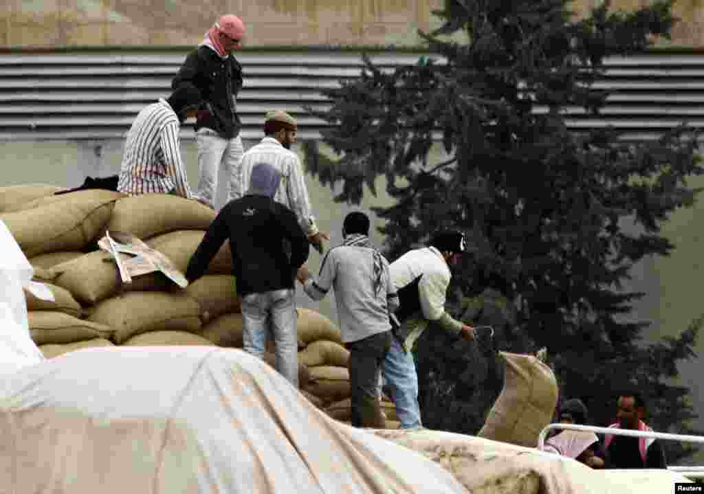 2012年11月26日，从土耳其尚勒乌尔法省的边境城镇杰伊兰帕纳尔可以看到自由叙利亚军成员以及来自叙利亚城镇拉斯艾因的男性民众从卡车上卸下装着面的口袋。
