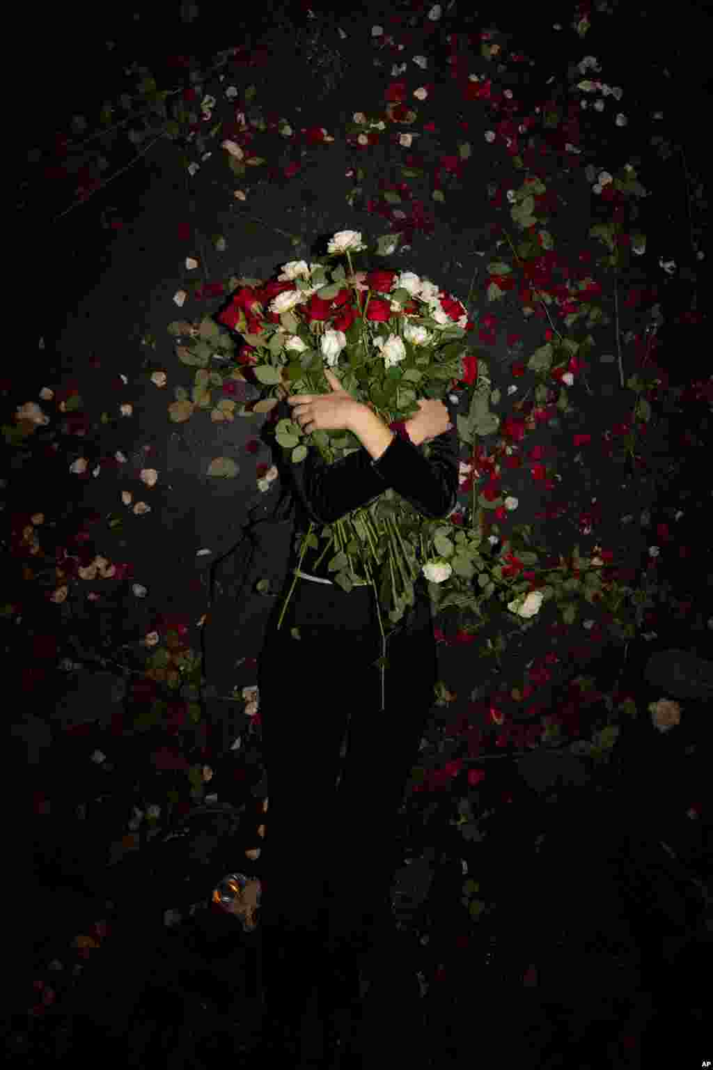 An Israeli protester holds flowers as she lies on the road during a demonstration against Prime Minister Benjamin Netanyahu near the Prime Minister&#39;s residence in Jerusalem, Aug. 15, 2020.