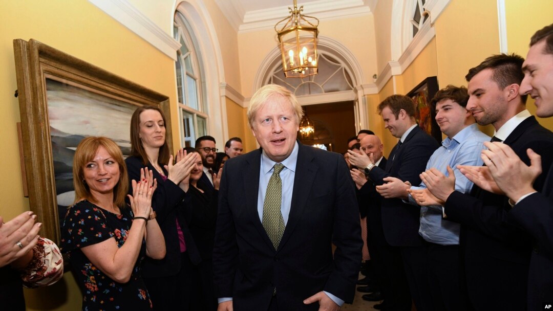 Perdana Menteri Boris Johnson disambut oleh anggota stafnya saat tiba di kantor perdana menteri, 10 Downing Street, London, setelah bertemu Ratu Elizabeth, 13 Desember 2019. 