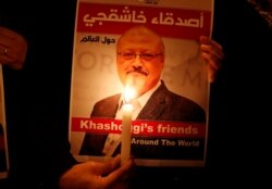 FILE - A protester holds a poster with a picture of slain Saudi journalist Jamal Khashoggi, outside Saudi Arabia's consulate in Istanbul, Turkey, Oct. 25, 2018.