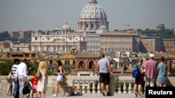 FILE - Tourists take pictures of Saint Peter's Basilica from Pincio terrace in downtown Rome, Italy, Aug. 3, 2017. 