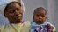 FILE - Two-month-old Lahya Kathembo, whose mother and father died of Ebola, is carried by a nurse waiting for test results at an Ebola treatment center in Beni, DRC, July 17, 2019.