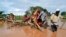 FILE —Residents of Chamwana Muma village walk through flood water after using a makeshift bridge to cross the swollen River Tana, in Tana Delta, Kenya, on Wednesday Nov. 15, 2023. 