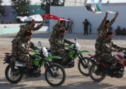 FILE - Fighters of Syrian National Army, backed by Turkey, ride on motorbikes during a graduation ceremony in the city of al-Bab, Syria, Aug. 5, 2018.