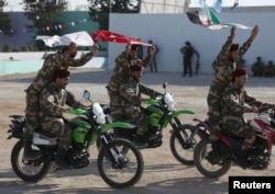 FILE - Fighters of Syrian National Army, backed by Turkey, ride on motorbikes during a graduation ceremony in the city of al-Bab, Syria, Aug. 5, 2018.