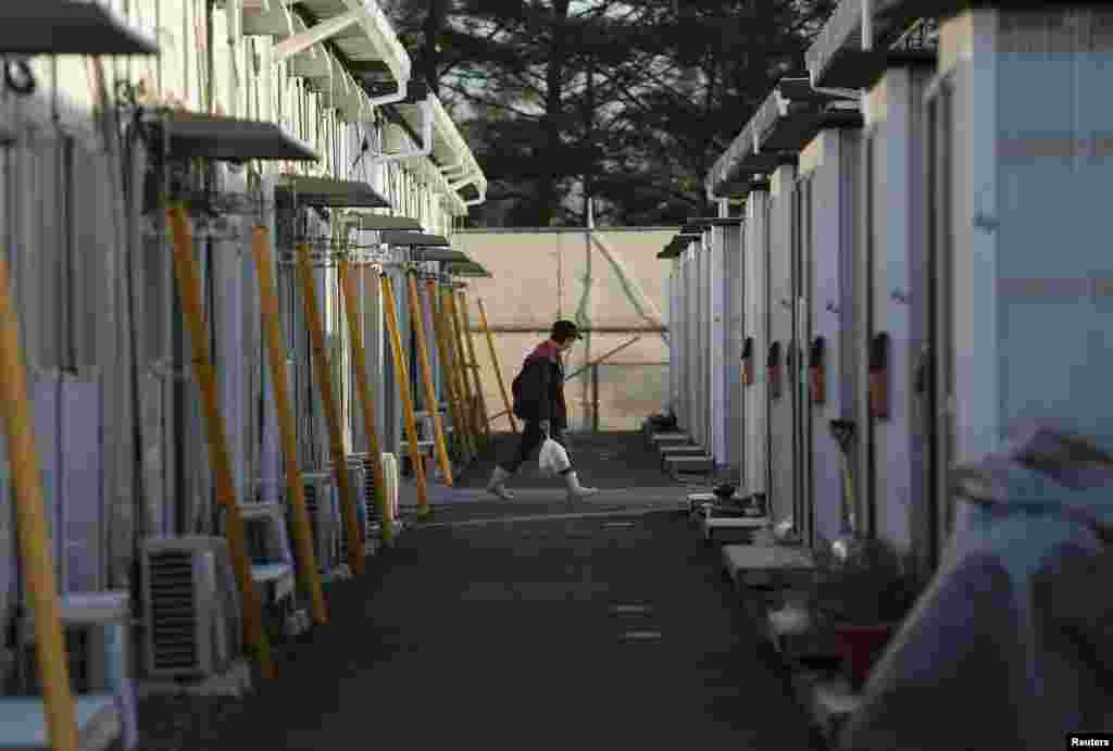 Seorang warga masuk ke dalam kompleks perumahan sementara tempat tinggal warga yang dievakuasi dari Tamura di Funahiki, Fukushima (1/4).