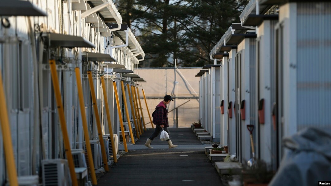 Seorang warga masuk ke dalam kompleks perumahan sementara tempat tinggal warga yang dievakuasi dari Tamura di Funahiki, Fukushima (1/4).