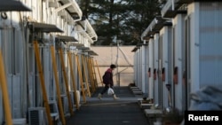 Seorang warga masuk ke dalam kompleks perumahan sementara tempat tinggal warga yang dievakuasi dari Tamura di Funahiki, Fukushima (1/4).