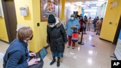 Un trabajador registra a residentes de los Apartamentos William Reid, en un sitio de vacunación contra el COVID-19 en NYCHA un complejo habitacional en Brooklyn, Nueva York, el sábado 23 de enero de 2021.