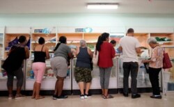 FILE - People wait in line to buy goods in a state store in downtown Havana, Cuba, May 10, 2019.