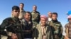 Elder Peshmerga fighter and now a volunteer, Omar Mirhan stands with his fellow Peshmerga on a hill overlooking the area of Makhmour which the Peshmerga won back from Islamic State in 2014, March 8, 2016. (S. Behn/VOA)