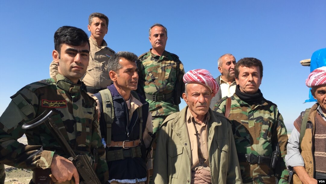 Elder Peshmerga fighter and now a volunteer, Omar Mirhan stands with his fellow Peshmerga on a hill overlooking the area of Makhmour which the Peshmerga won back from Islamic State in 2014, March 8, 2016. (S. Behn/VOA)