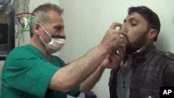 FILE - This video image from an anti-Bashar Assad activist group shows a Syrian man being treated with an inhaler in Kfar Zeita, north of Damascus, after what witnesses said was a chlorine gas attack, April 18, 2014.