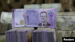 FILE - Syrian pounds are pictured inside an exchange currency shop in Azaz, Syria, Feb. 3, 2020. Rising prices and a drop in the currency's value have pushed ordinary Syrians to vent their anger in recent protests.