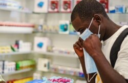In this Feb. 6, 2020 file photo, a man tries on a face mask at a pharmacy in Kitwe, Zambia.
