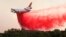 A DC-10 air tanker drops fire retardant along the crest of a hill to protect the two bulldozers below that were cutting fire lines at the River Fire (Mendocino Complex) near Lakeport, Calif., Aug. 2, 2018.