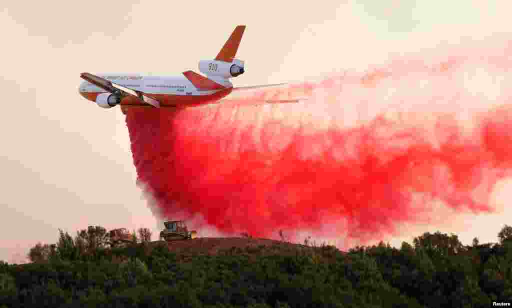 Pesawat tanker DC-10 menjatuhkan bahan pemadam kebakaran untuk melindungi petugas dengan buldozer yang sedang membuat parit pencegah kebakaran hutan di dekat Lakeport, California.