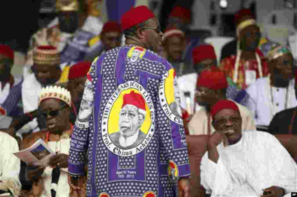 Wannan hoton wani basaraken Alumar kabilar ne shima yake sanye tufafinda&nbsp;akaduga hoton Chinua Achebe. A wajen wan nan janaizan donkarrama mamachin. 