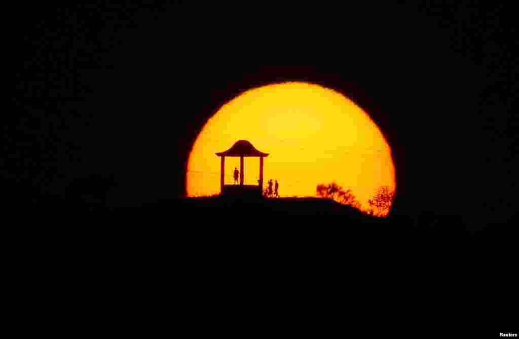 People are silhouetted against the setting sun at 'El Mirador de la Alemana' (The viewpoint of the German), as the summer's second heatwave hits Spain, in Malaga, southern Spain July 24, 2019.