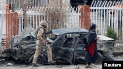 FILE - A member of Afghan security forces inspects a damaged vehicle at the site of a blast in Kabul, Afghanistan, Dec. 20, 2020. 