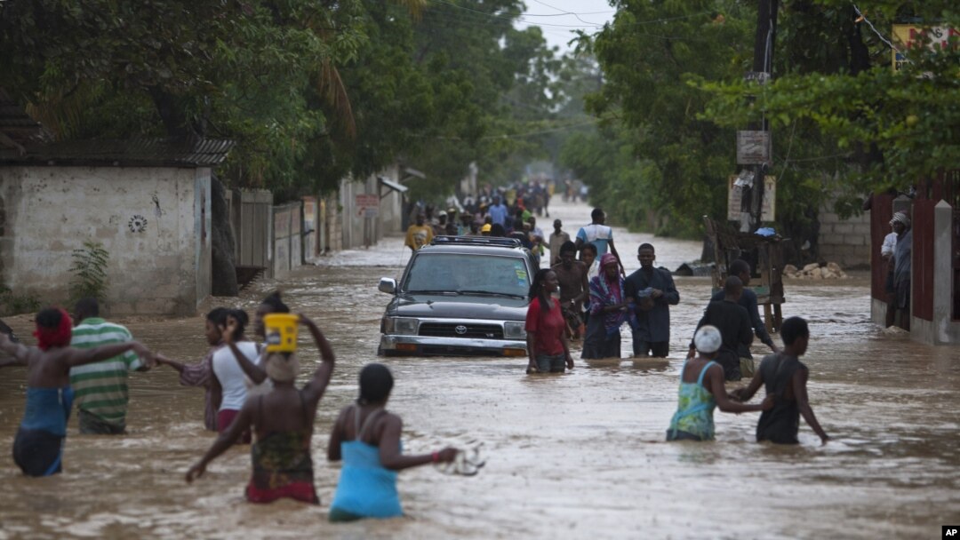 Warga Port-au-Prince, Haiti, mengarungi genangan banjir yang dipicu badai tropis Isaac. (Foto: AP/Dieu Nalio Chery)