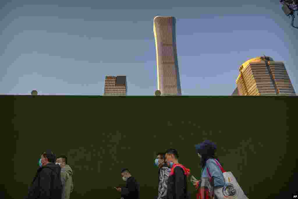 Commuters wearing face masks to protect against the coronavirus walk along a street in the central business district in Beijing, Friday, Oct. 16, 2020. Authorities have completed tests on more than 10 million people in the northern Chinese port city of Qi