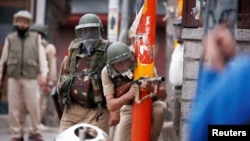 An Indian police officer aims his gun towards demonstrators, during a protest against the recent killings of Palestinian protesters on the Gaza-Israel border and the U.S. embassy move to Jerusalem, in Srinagar, May 18, 2018.