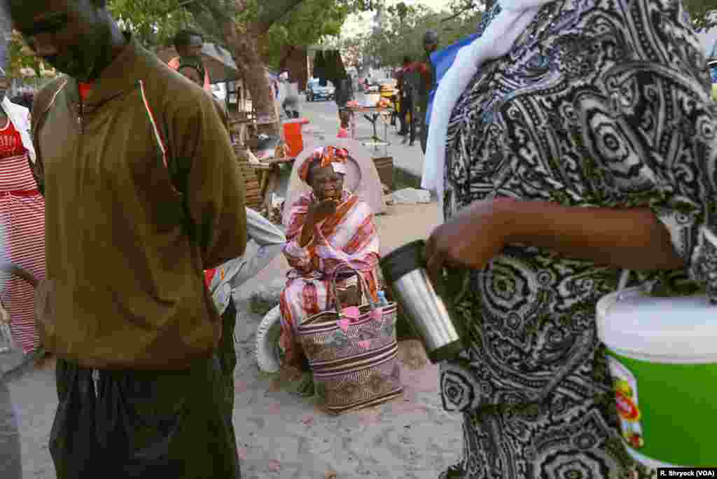 A woman yawns as she waits for her Ndogou meal. Just before the breaking of the fast, the streets of Dakar grow quiet except for small groups dotted along certain neighborhoods. These groups boil massive pots of local tea and coffee and make sandwiches.