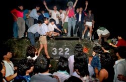 FILE - In this early June 4, 1989, photo, civilians with rocks stand on a military armored vehicle near Chang'an Boulevard in Beijing as violence escalated between pro-democracy protesters and Chinese troops, leaving hundreds dead overnight.