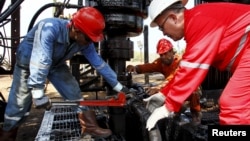 Men work at an oil pump in Lagunillas, Ciudad Ojeda, in the state of Zulia, Venezuela, March 20, 2015. 