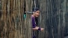 FILE - A refugee who fled Myanmar watches from behind a bamboo wall of a stilt house at Mae La refugee camp, on the Thai side of the Thailand-Myanmar border, July 21, 2014. Many of the 90,000 refugees in nine camps along the border have lived in them for decades.