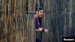 FILE - A refugee who fled Myanmar watches from behind a bamboo wall of a stilt house as Thai authorities conduct a census at Mae La refugee camp, near the Thailand-Myanmar border in Mae Sot district, Tak province, Thailand. Many refugees are hopeful about