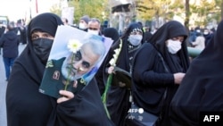 Iranian mourners hold a picture of slain top Iranian commander Qasem Soleimani in Tehran during a funeral procession for 150 Iranian soldiers killed in the Iran-Iraq war (1980-1988), whose bodies were recovered from battlefields, January 6, 2022. 