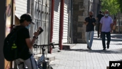 Palestinian men walk in front of closed shops in the occupied West Bank city of Ramallah, on July 13, 2020, amid the novel coronavirus pandemic crisis. 