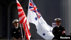 资料照：日澳海军在澳大利亚悉尼一军事基地举行联合军演前两国军人在日澳两军旗帜旁合影。（2016年4月19日）