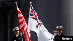 Crew members from the Japanese Maritime Self-Defense force ship Umigiri stand on deck between Japan's Self-Defense Force flag alongside an Australian flag before joint exercises in Australia. 